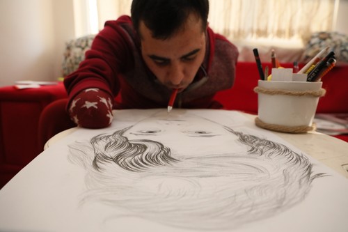 معجزة فنية.. الرسام التركي "آقغون" فقد ذراعيه صغيراً فأبدعت شفتاه  1516741964382